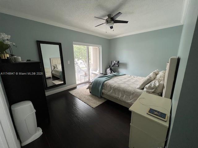 bedroom with a textured ceiling, dark wood-type flooring, a ceiling fan, access to exterior, and ornamental molding