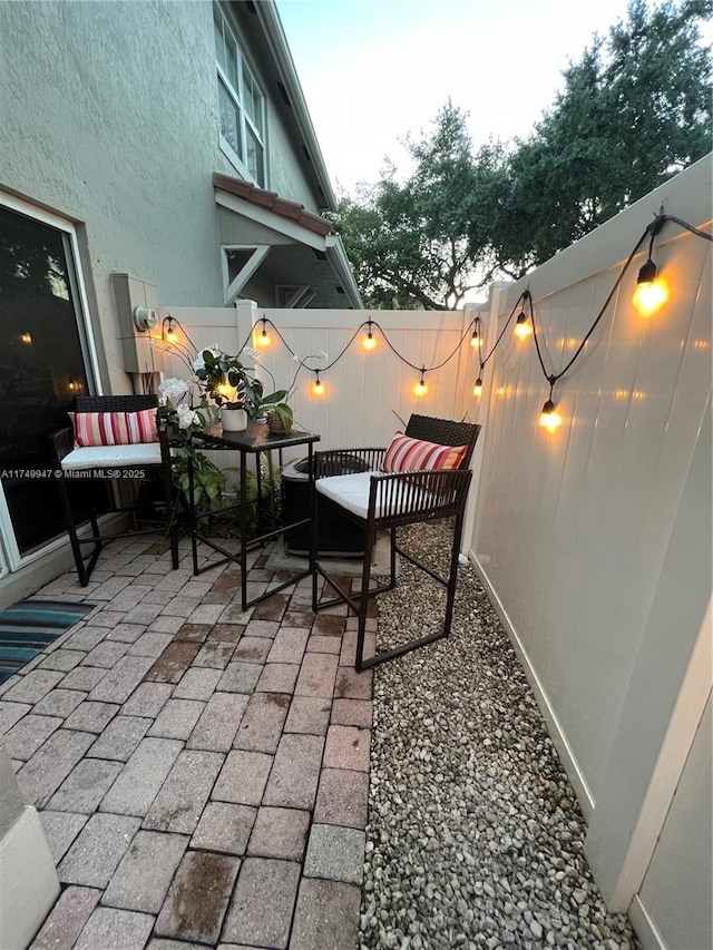 patio terrace at dusk with outdoor dining space and a fenced backyard