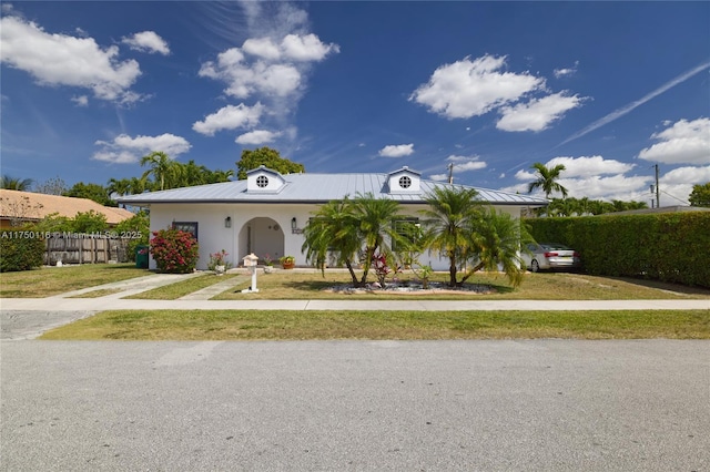 view of front of property with metal roof, stucco siding, fence, and driveway