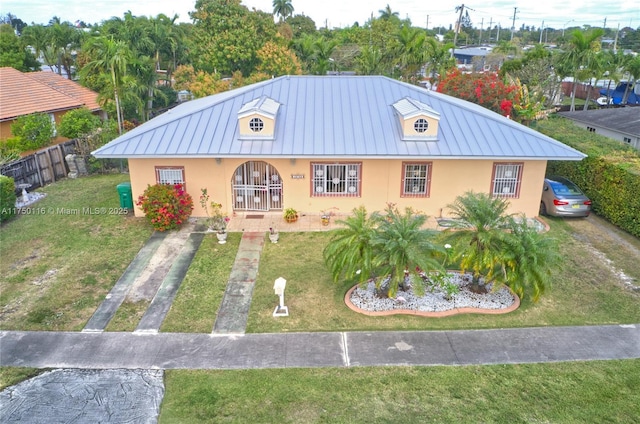 view of front facade featuring stucco siding, a front lawn, metal roof, and a standing seam roof