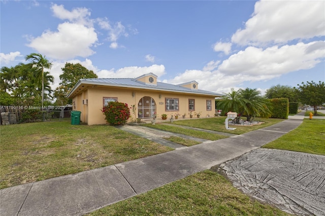 view of front of house featuring metal roof, a front yard, fence, and stucco siding