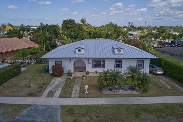 view of front of home featuring metal roof, driveway, stucco siding, and a front lawn