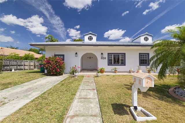 view of front facade with stucco siding, fence, and a front yard