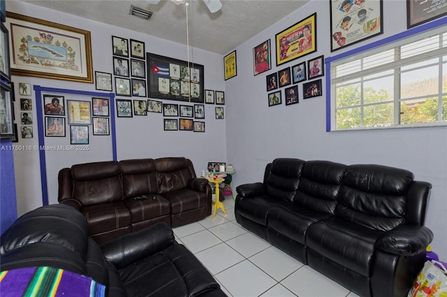 living area with a textured ceiling, light tile patterned flooring, and visible vents