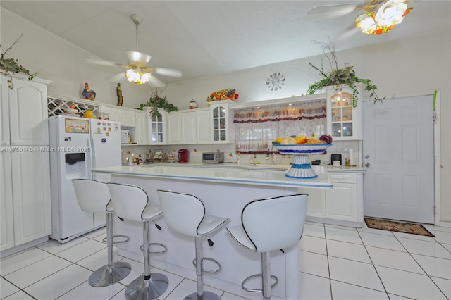 10745 Westwood Lake Dr, Miami, FL 33165 - kitchen featuring white refrigerator with ice dispenser, a ceiling fan, a kitchen breakfast bar, and light tile patterned floors
