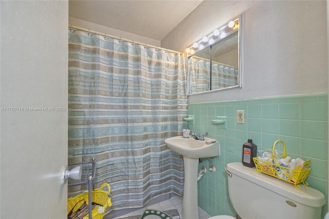 full bath featuring a wainscoted wall, a shower with shower curtain, toilet, and tile walls
