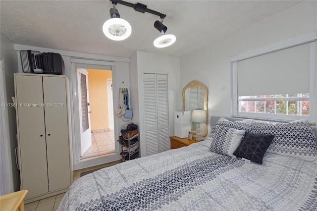 bedroom with a closet, ceiling fan, a textured ceiling, and light tile patterned floors