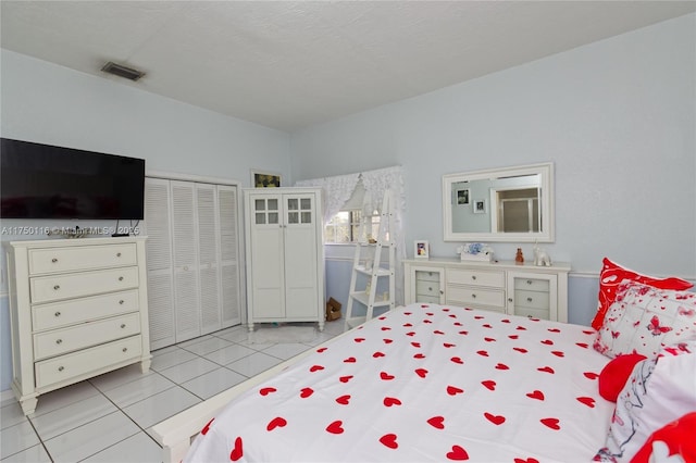 bedroom with light tile patterned flooring, visible vents, a closet, and a textured ceiling