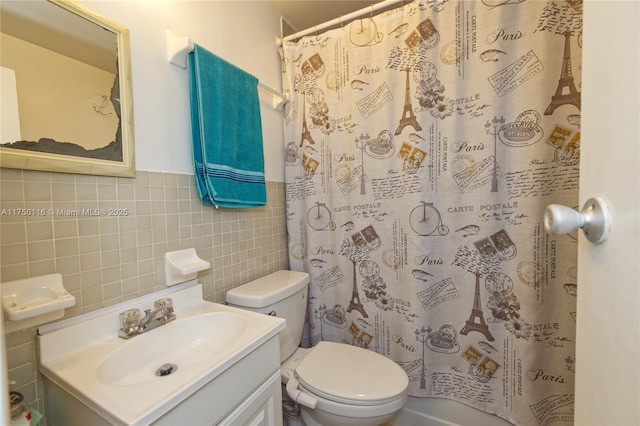 full bath with a wainscoted wall, toilet, curtained shower, vanity, and tile walls