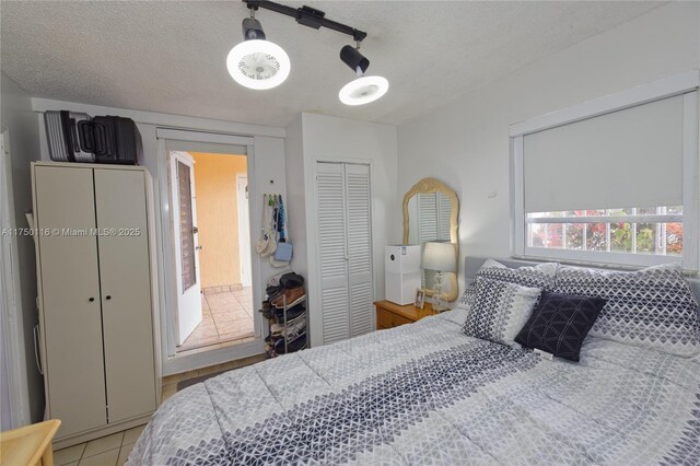 bedroom with a ceiling fan, light tile patterned flooring, a closet, and a textured ceiling