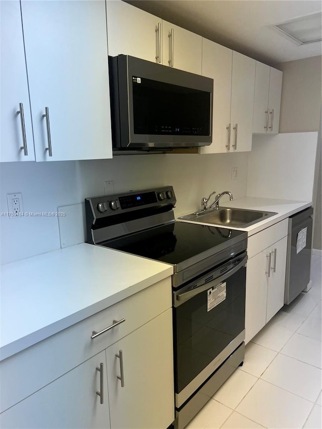 kitchen with light tile patterned floors, appliances with stainless steel finishes, light countertops, and a sink