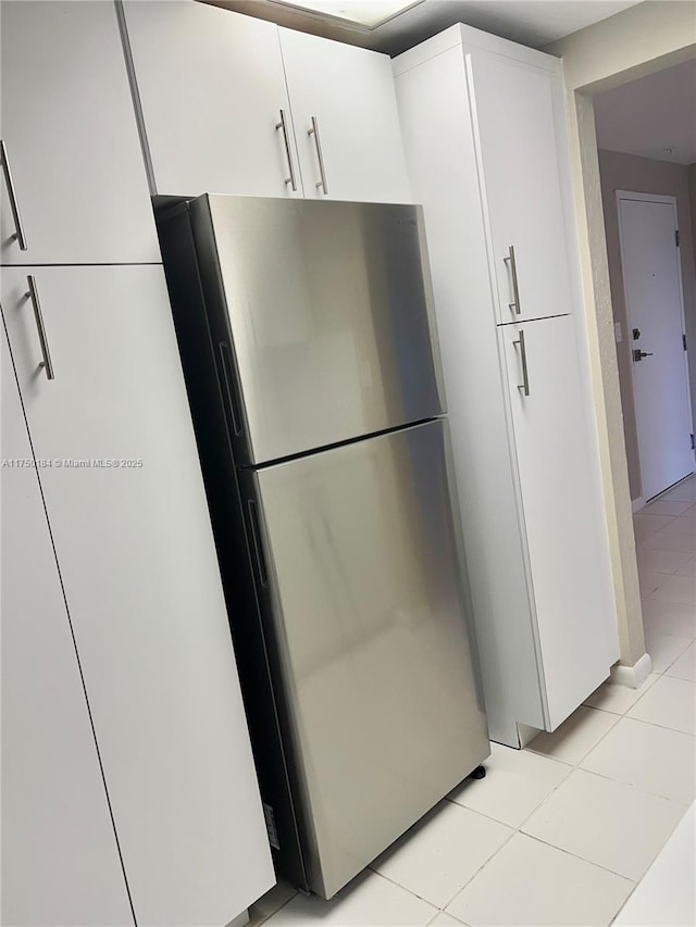 kitchen featuring freestanding refrigerator, white cabinetry, and light tile patterned floors