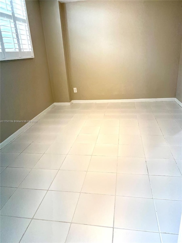 spare room with light tile patterned floors and baseboards