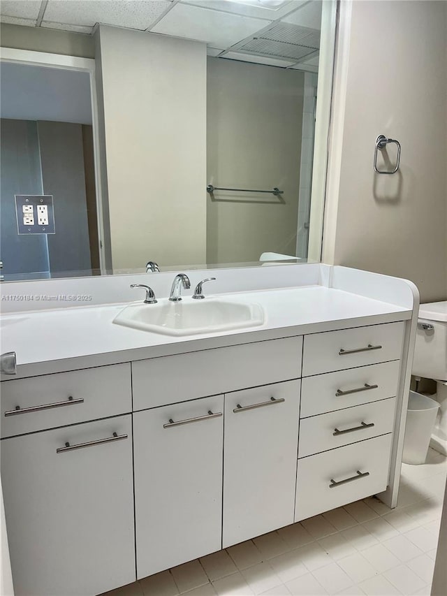 bathroom featuring a drop ceiling, vanity, and toilet