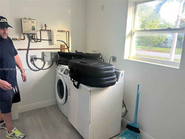 clothes washing area featuring light wood-type flooring, laundry area, washing machine and clothes dryer, and baseboards