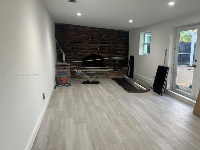 unfurnished living room with light wood-style flooring, a fireplace, baseboards, and visible vents