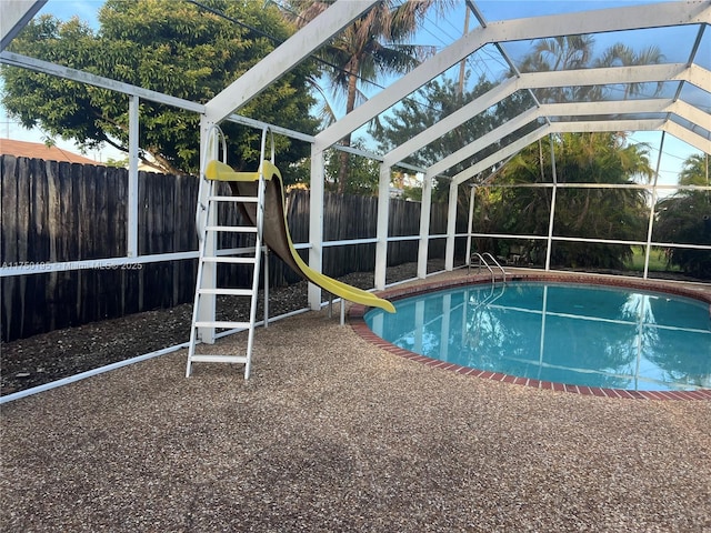 view of swimming pool with a water slide, a fenced backyard, a lanai, and a fenced in pool