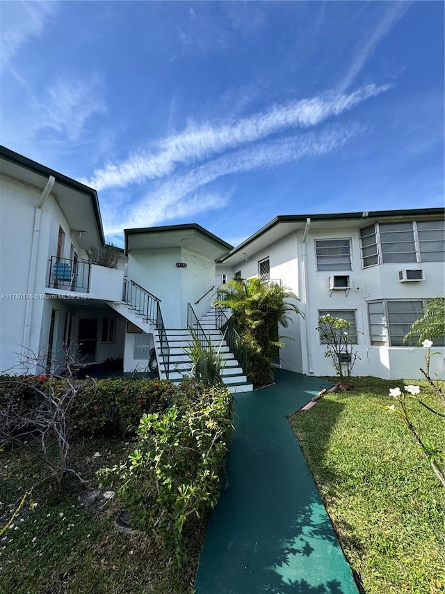 view of side of home with a yard, stairway, and stucco siding