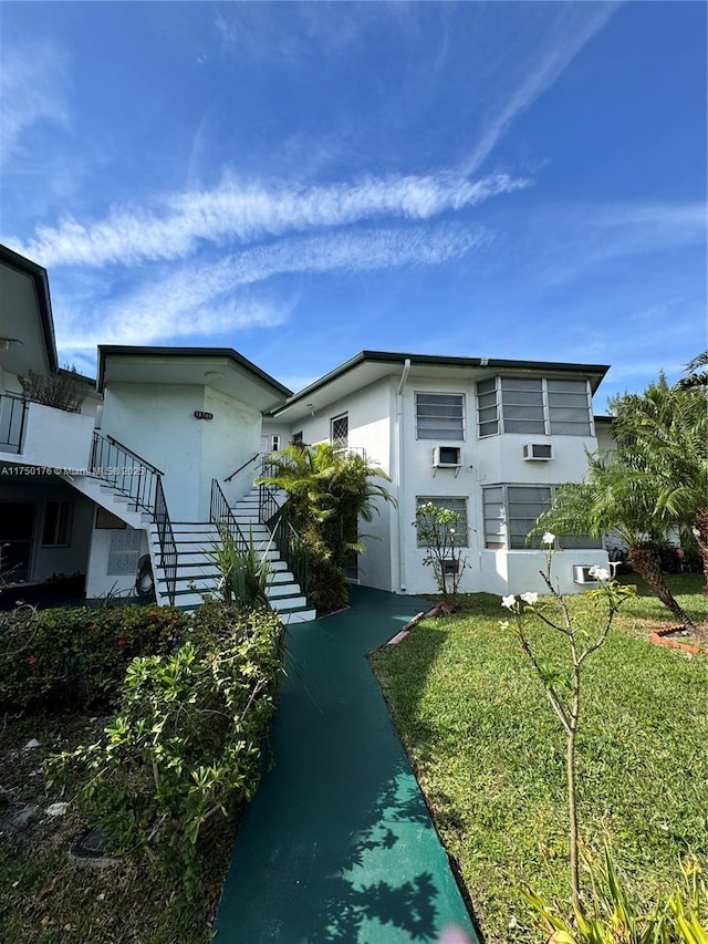 exterior space with a yard, stairway, and stucco siding