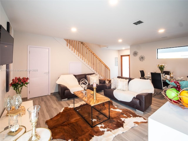 living room featuring light wood-type flooring, visible vents, stairway, and recessed lighting