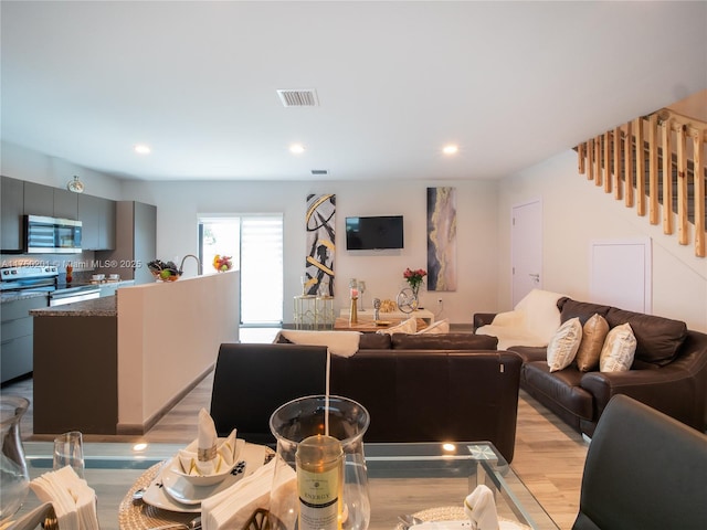 living area featuring stairway, light wood-type flooring, and recessed lighting