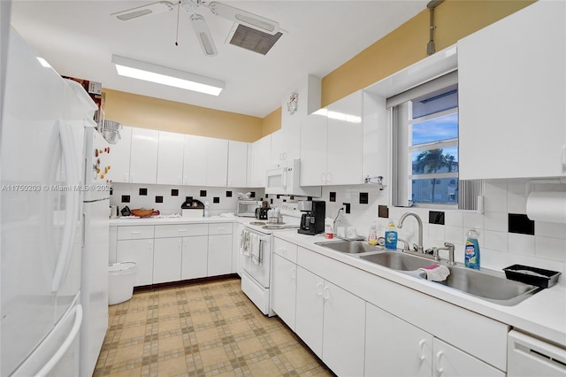 kitchen featuring white appliances, white cabinetry, light countertops, and a sink