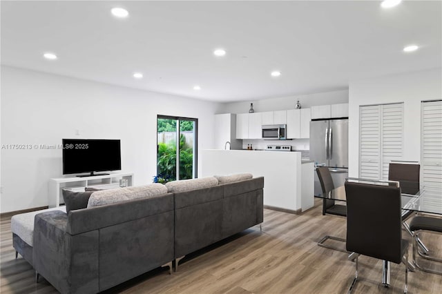 living room featuring recessed lighting, baseboards, and light wood finished floors