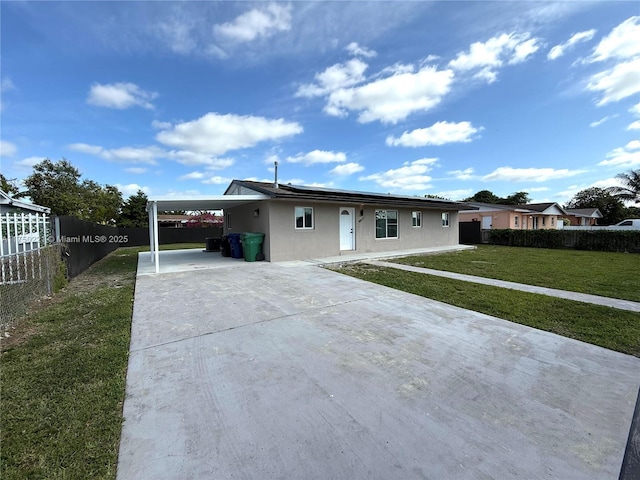 view of front facade with driveway, an attached carport, fence, a front lawn, and stucco siding