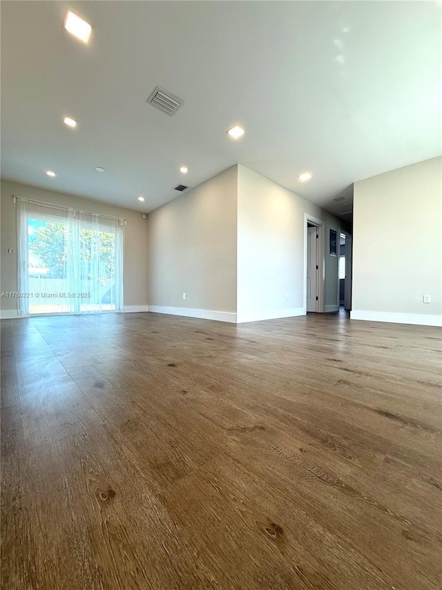 spare room featuring dark wood-type flooring, recessed lighting, visible vents, and baseboards