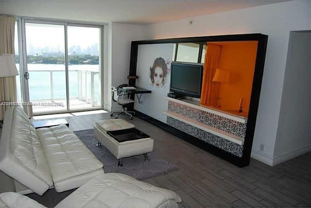 living room with a water view, baseboards, and wood finished floors