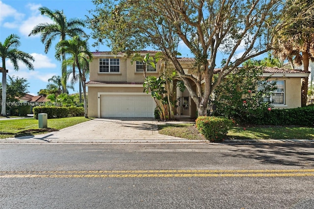 mediterranean / spanish-style home featuring a garage, concrete driveway, a tile roof, and stucco siding