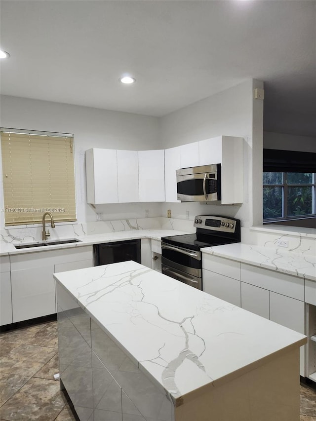 kitchen featuring a sink, stainless steel appliances, a kitchen island, and white cabinetry