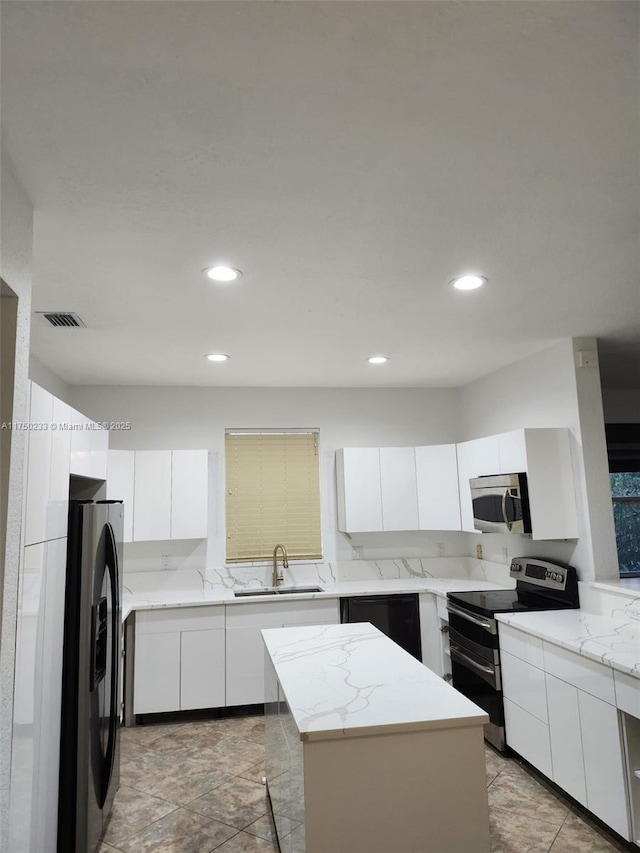 kitchen featuring modern cabinets, a kitchen island, appliances with stainless steel finishes, white cabinetry, and a sink