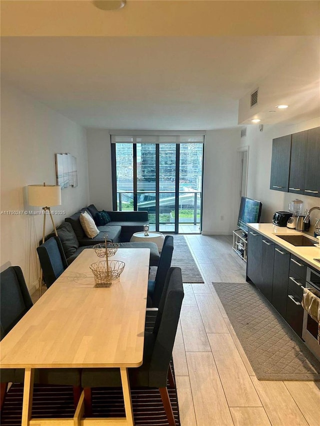 dining space featuring floor to ceiling windows, visible vents, and wood tiled floor