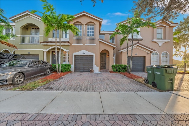 view of front of property featuring decorative driveway, an attached garage, a tile roof, and stucco siding