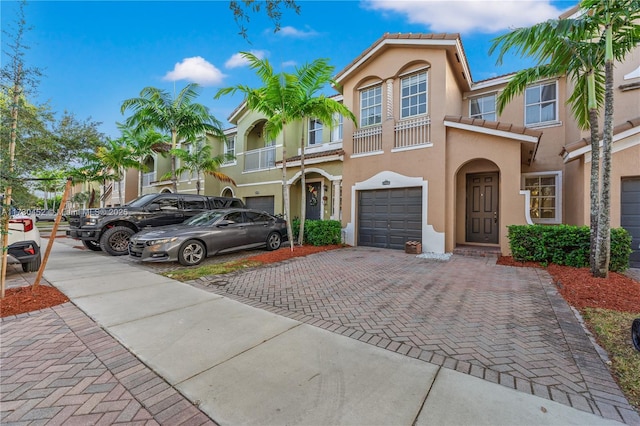 view of front facade featuring a garage, decorative driveway, a tile roof, and stucco siding