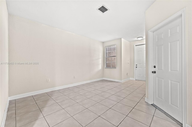 empty room featuring light tile patterned floors, visible vents, and baseboards