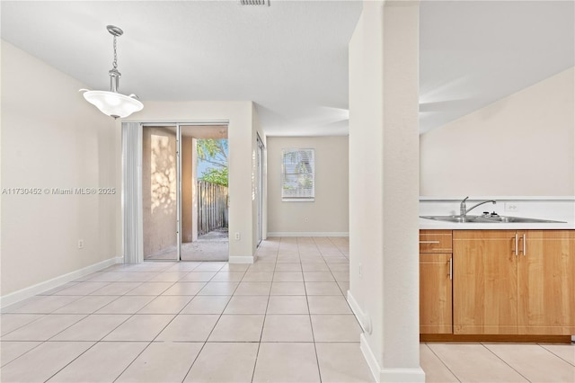 interior space featuring light tile patterned flooring, a sink, visible vents, and baseboards