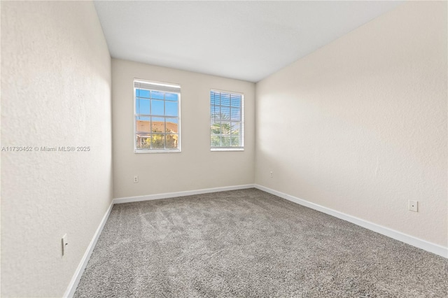 empty room with a textured wall, carpet, and baseboards