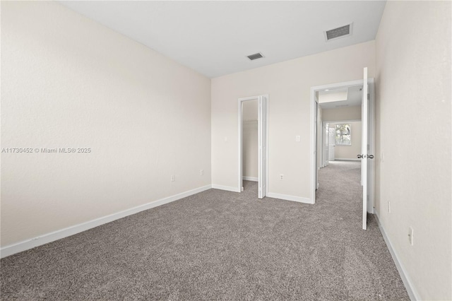 unfurnished bedroom with baseboards, a spacious closet, visible vents, and carpet flooring