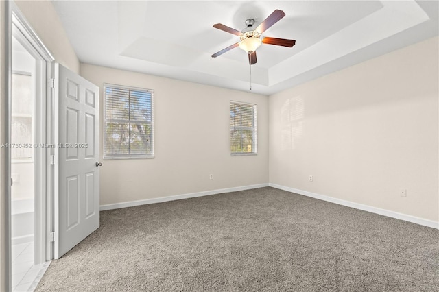 unfurnished bedroom with baseboards, a raised ceiling, and light colored carpet