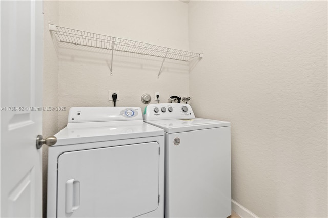 laundry area featuring a textured wall, laundry area, and washing machine and dryer