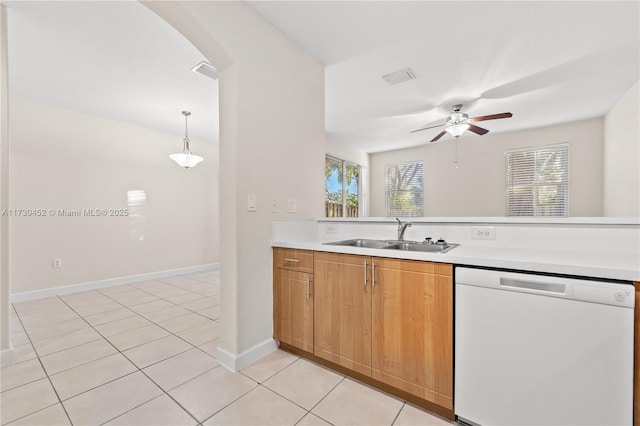 kitchen featuring pendant lighting, light tile patterned floors, light countertops, white dishwasher, and a sink