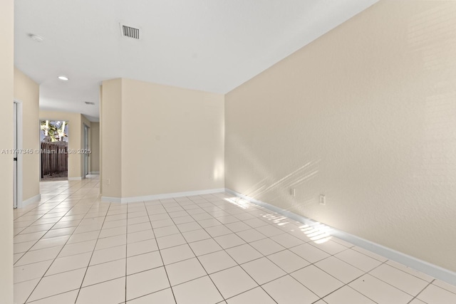 empty room featuring light tile patterned flooring, visible vents, and baseboards