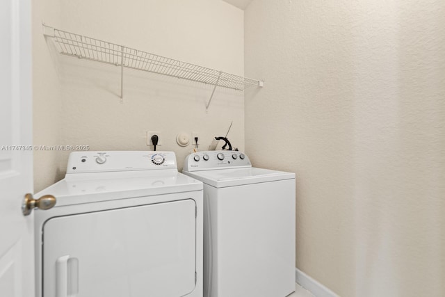 washroom featuring laundry area, baseboards, and washer and dryer