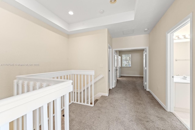 hall featuring recessed lighting, light colored carpet, an upstairs landing, baseboards, and a tray ceiling