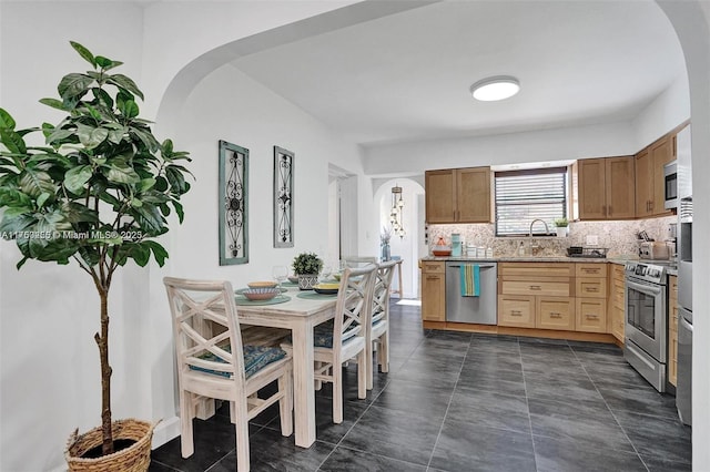 kitchen featuring stainless steel appliances, arched walkways, light countertops, and a sink