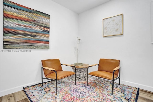 sitting room with baseboards and wood finished floors