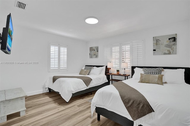 bedroom featuring wood finished floors, visible vents, and baseboards