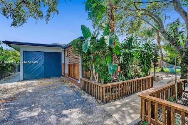 view of front facade with driveway, a garage, and fence